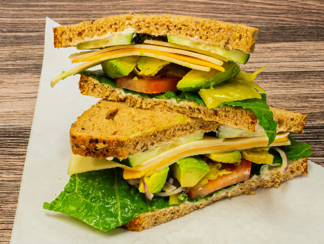 Stacked vegetable and cheese deli sandwiches on a catering tray.